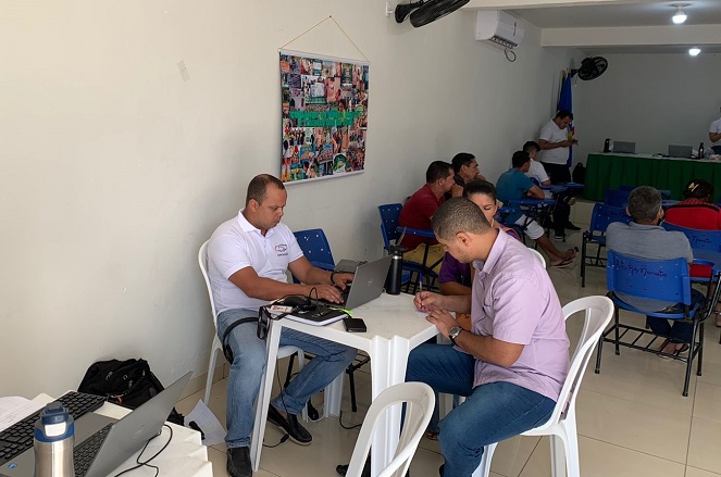 Pessoas sendo atendidas no município de Alto Alegre do Maranhão. Eles estão sentados, de frente para o outro. Há uma mesa com computador.