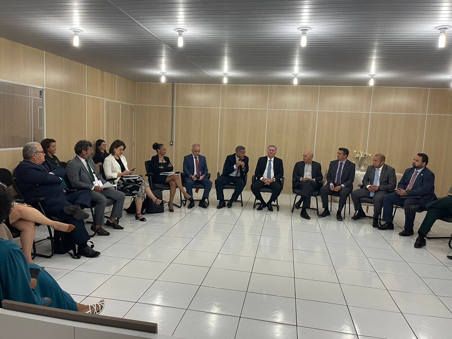 Foto colorida. Autoridades conversam sentadas em disposição circular em uma sala, com o desembargador ronaldo maciel fazendo uso da palavra