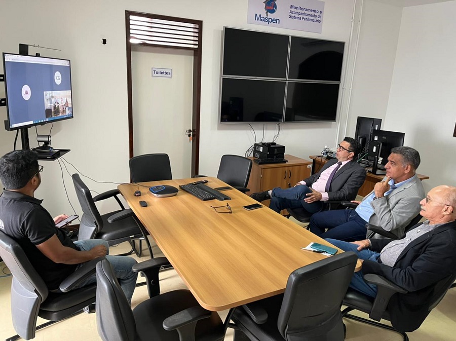 Fotografia colorida. desembargador ronaldo maciel e juízes douglas martins e josé costa, em mesa de reunião em sala da UMF, dialogando por meio de sistema de videoconferencia