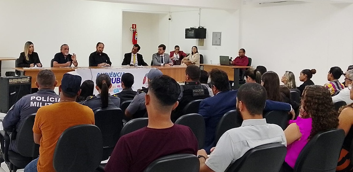 Foto horizontal de evento. Ouvidoria realiza audiência pública em Porto Franco. A imagem mostra uma audiência pública em uma sala. Na frente da sala, há uma mesa comprida com seis pessoas, todas vestidas formalmente. Atrás da mesa, vê-se um banner com o texto ¿AUDIÊNCIA PÚBLICA¿. O público está sentado em cadeiras distribuídas pela sala e inclui alguns membros da Polícia Militar. Eles aparecem de costas para a câmera. O ambiente é bem iluminado e organizado, com um extintor de incêndio fixado na parede ao fundo. Também há um amplificador de som à esquerda da imagem e um notebook posicionado na mesa à direita.

A imagem transmite o cenário de uma reunião formal com participação ativa de diferentes segmentos da sociedade.