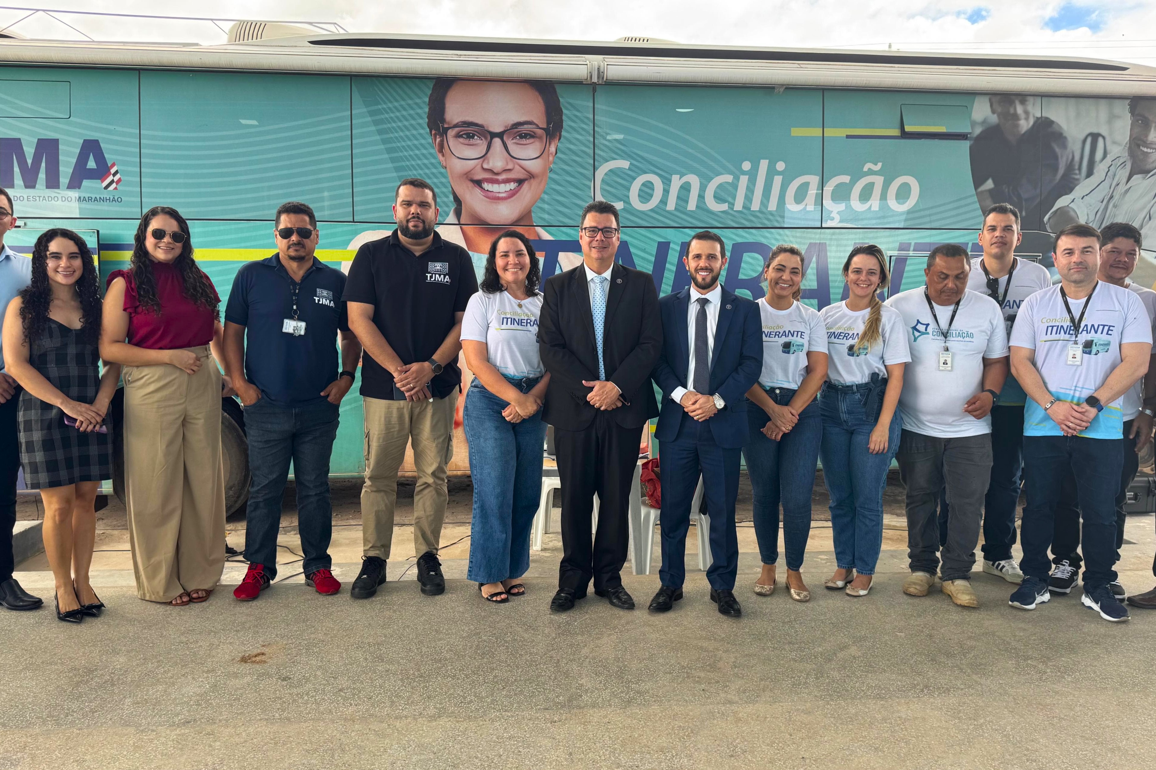 pessoas na frente de um onibus, em pé.