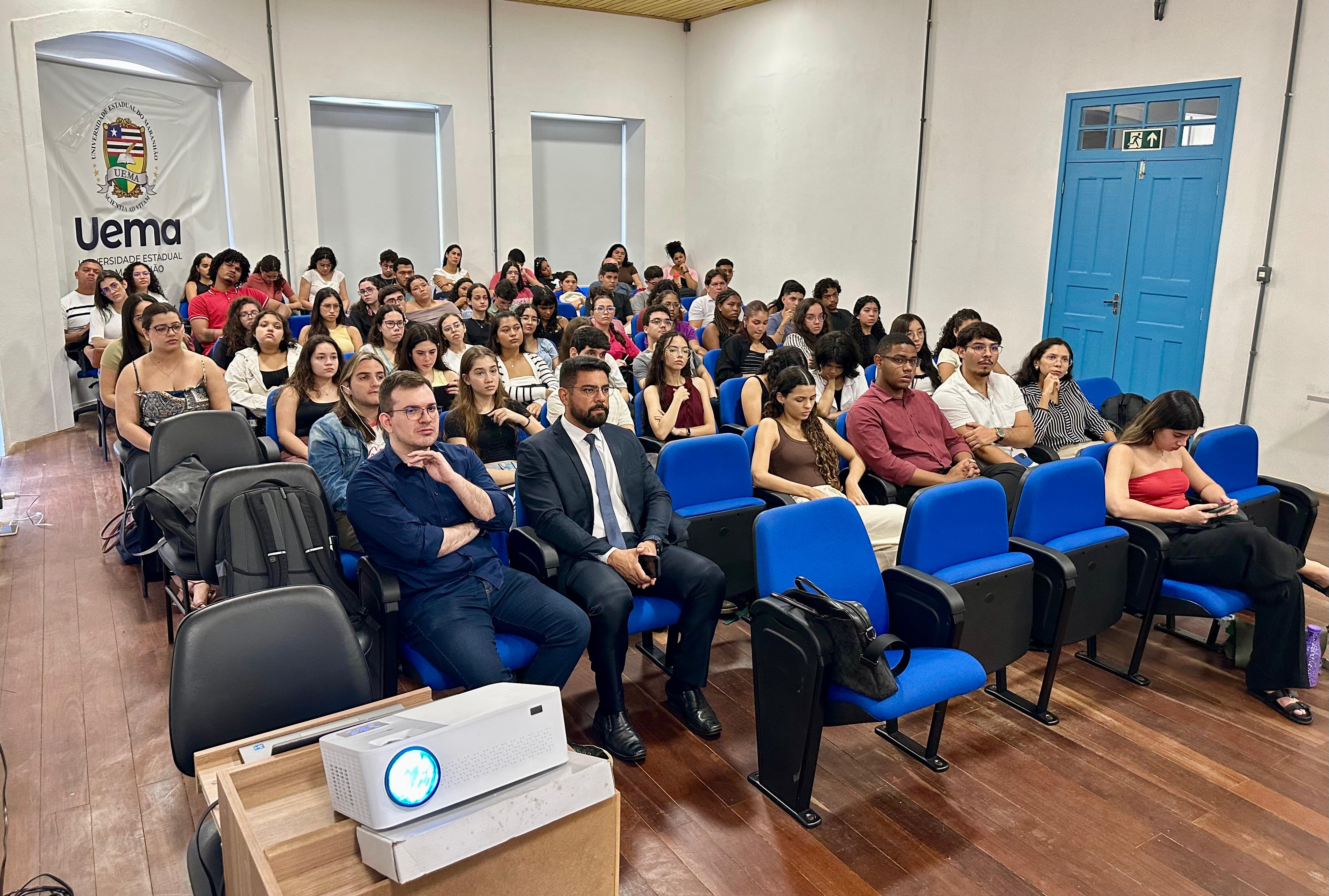 Foto colorida mostra estudantes sentados em auditório da UEMA durante palestra ministrada pelo TJMA