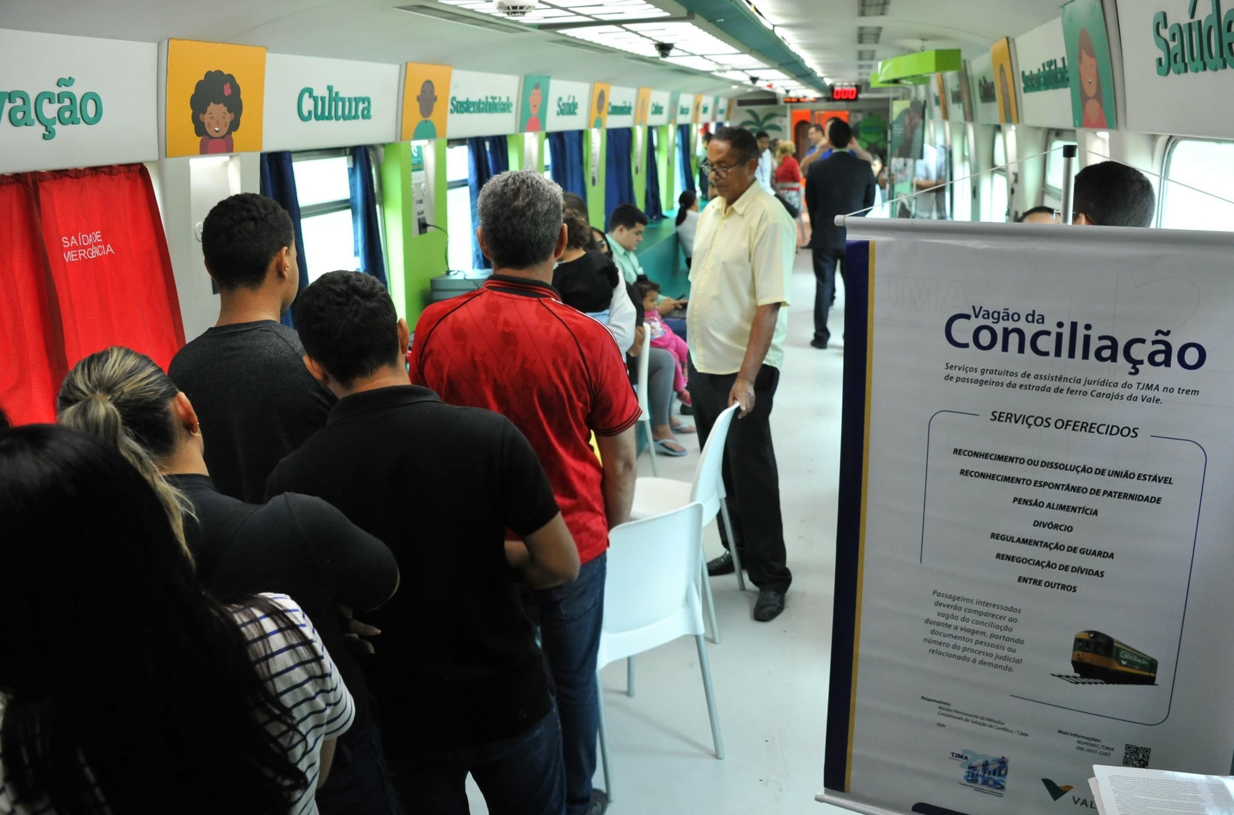 A imagem mostra um vagão de trem adaptado para oferecer serviços jurídicos gratuitos. Há várias pessoas em fila aguardando atendimento. No fundo, há divisórias com palavras como "Saúde", "Cultura", "Sustentabilidade", "Cidadania" e "Educação". À direita, um banner destaca os serviços oferecidos pelo **Vagão da Conciliação**, incluindo:

- Reconhecimento ou dissolução de união estável  
- Reconhecimento espontâneo de paternidade  
- Pensão alimentícia  
- Divórcio  
- Regulamentação de guarda  
- Renegociação de dívidas  

A iniciativa evidencia a democratização do acesso à Justiça para passageiros da Estrada de Ferro Carajás, promovendo a solução de conflitos de forma prática e acessível. Uma excelente ação de inclusão social!