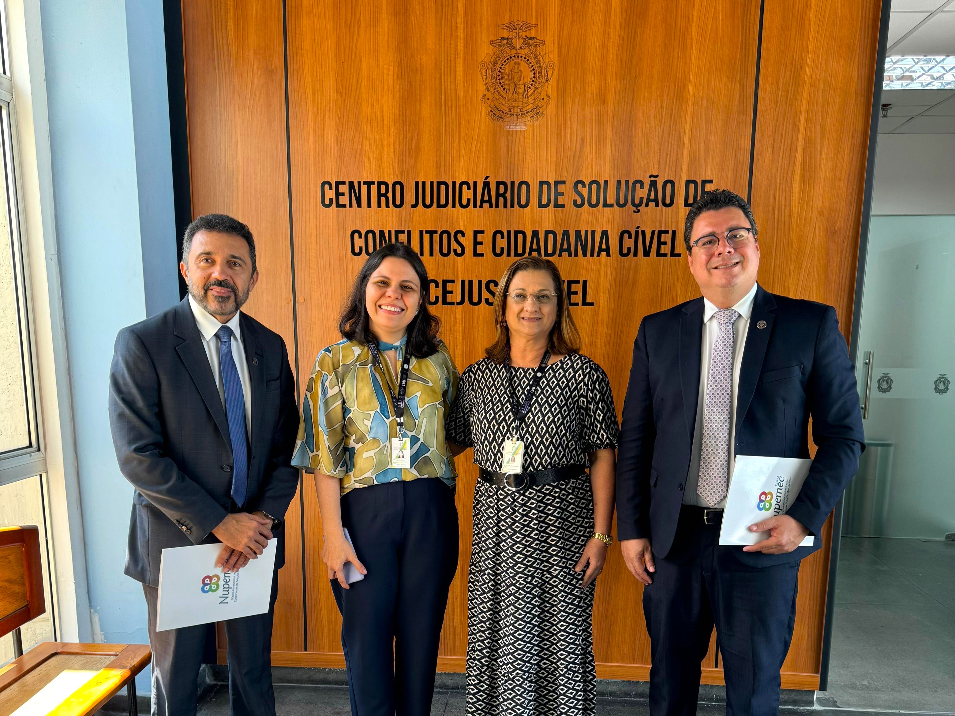 A imagem mostra uma grande configuração circular de reunião dentro de uma sala com um teto em forma de cúpula. Há várias mesas dispostas em um círculo aberto, e muitas pessoas estão sentadas ao redor, voltadas para o centro, onde há arranjos florais. Os participantes parecem estar envolvidos em um evento formal ou conferência. O ambiente sugere uma atmosfera de discussão ou negociação, com cada pessoa tendo visibilidade igual uma da outra devido ao arranjo circular.
