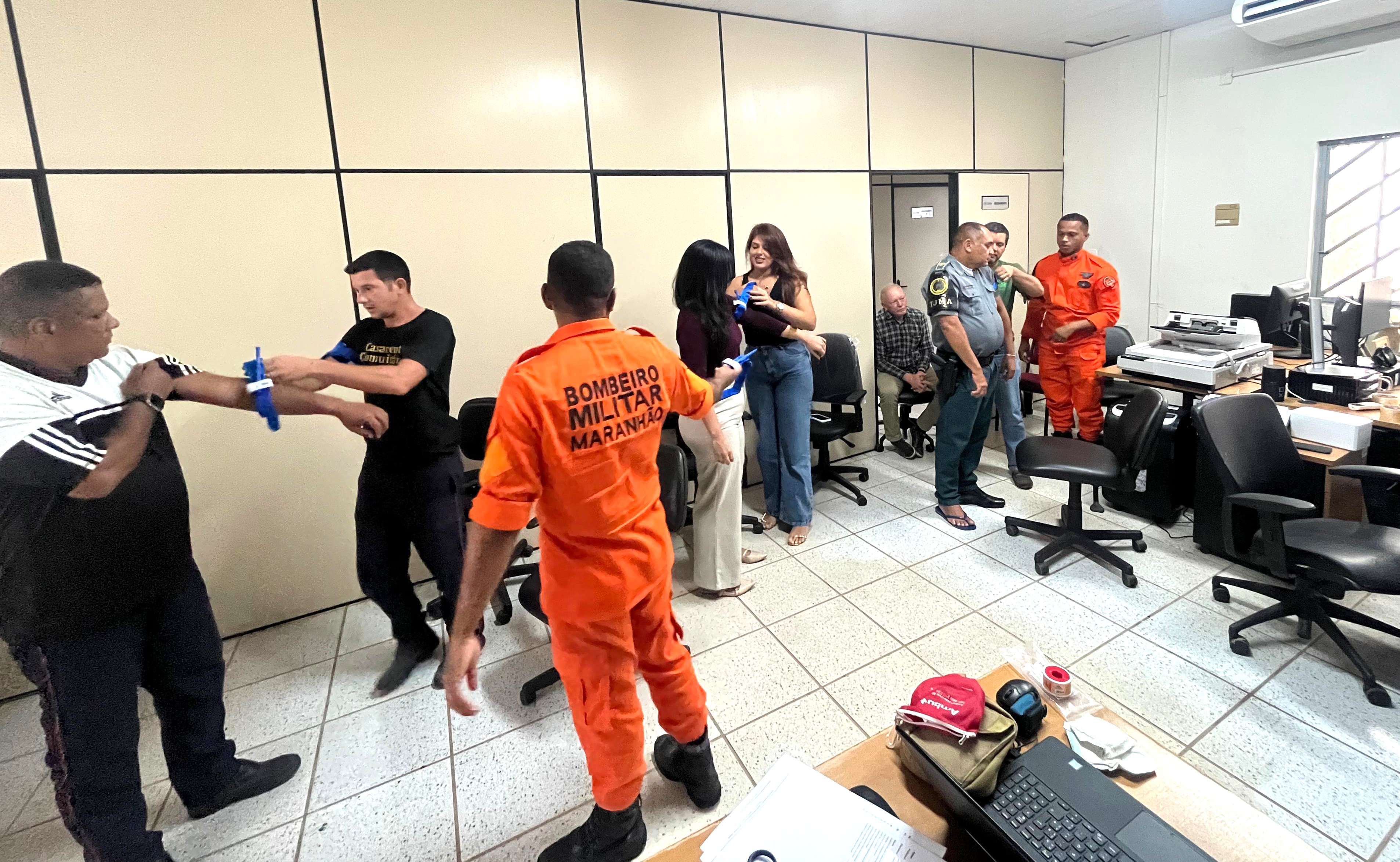 Foto colorida mostra duas pessoas em pé durante treinamento e brigada de incêndio em uma sala no Fórum