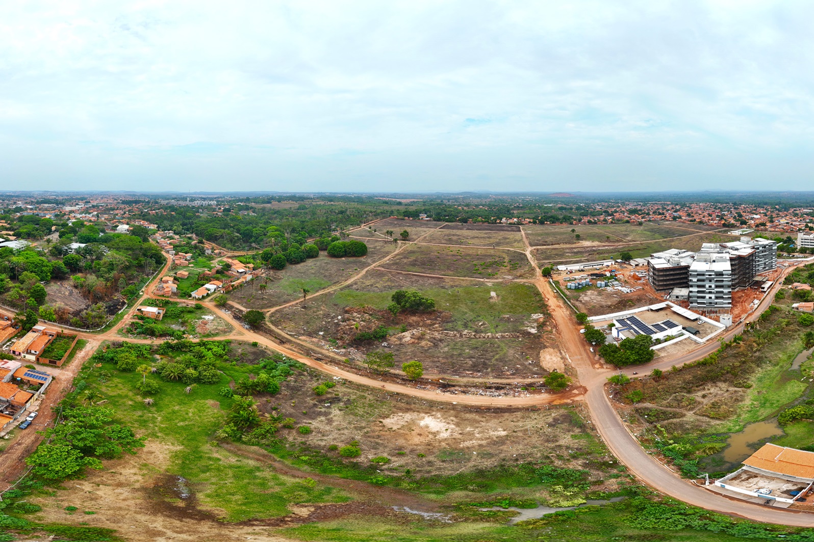 A imagem mostra quatro pessoas em um canteiro de obras. Todas as pessoas estão usando capacetes de segurança. Três das pessoas estão vestindo camisas sociais (uma rosa, uma azul clara e uma branca) e calças compridas, enquanto uma pessoa está vestindo uma camisa preta e jeans. A pessoa no centro parece estar gesticulando ou apontando para algo, possivelmente dando instruções ou explicações.