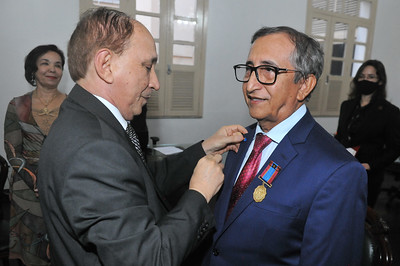 Foto colorida do presidente Lourival Serejo, em pé, botando medalha no desembargador Raimundo Barros