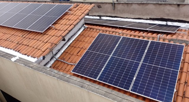 Imagem colorida. Foto de placas de energia solar em dois telhados de unidade judicial de Paço do Lumiar.