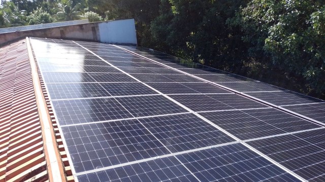 Imagem colorida. Foto de placas de energia solar em telhado de unidade judicial da Raposa.