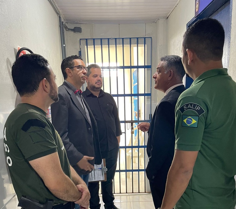 foto colorida. foto em local interno,  mostrando o desembargador ronaldo maciel, o juiz douglas martins, o secretário murillo andrade e policiais em frente a uma cela prisional