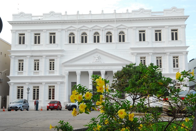 Imagem colorida. Foto da fachada do Tribunal de Justiça do Maranhão. Em primeiro plano, flores amarelas. Foto: Ribamar Pinheiro