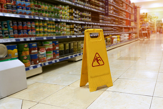 imagem de um corredor de supermercado com uma placa amarela  avisando sobre chão molhado