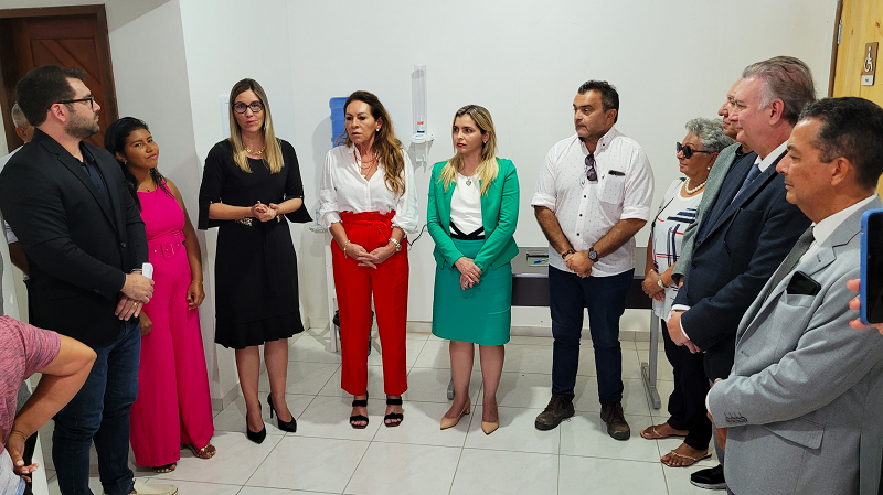 mulher fala observada por outras pessoas que estão em pé ao lado