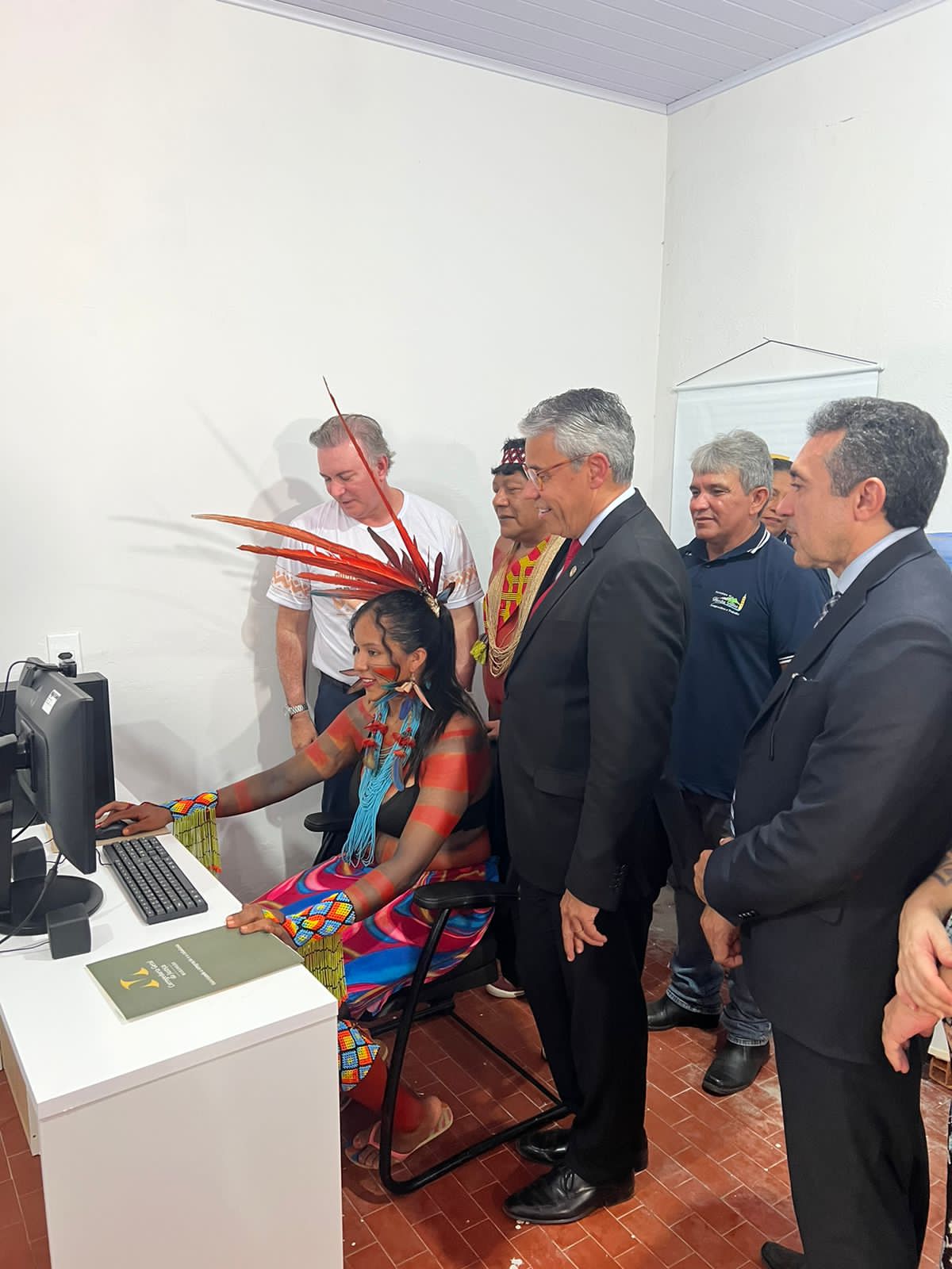 grupo de pessoas, entre elas o corregedor-geral da justiça, o presidente do TJ e uma mulher indígena, em frente ao computador
