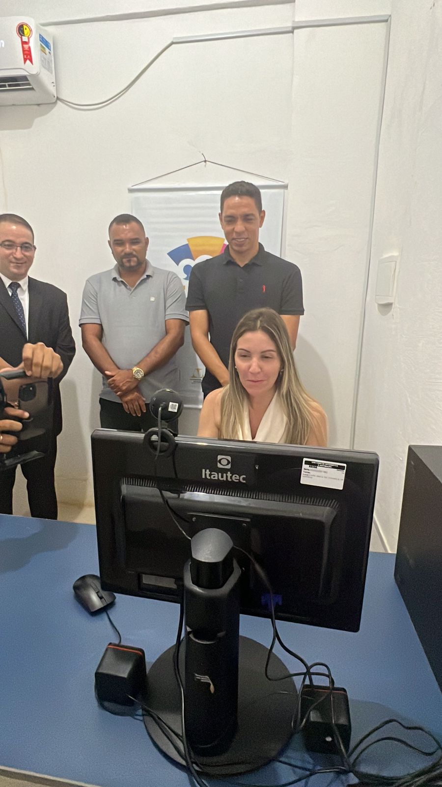 juíza teresa nina em chamada de vídeo durante inauguração da 99ª sala da justiça, ao fundo autoridades observam