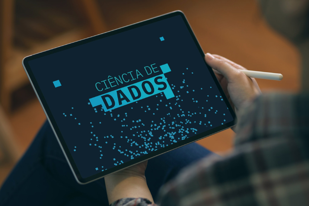 Imagem de mãos que seguram um tablet. Na tela o nome Ciência de Dados, com pequenos quadrados azul claro.