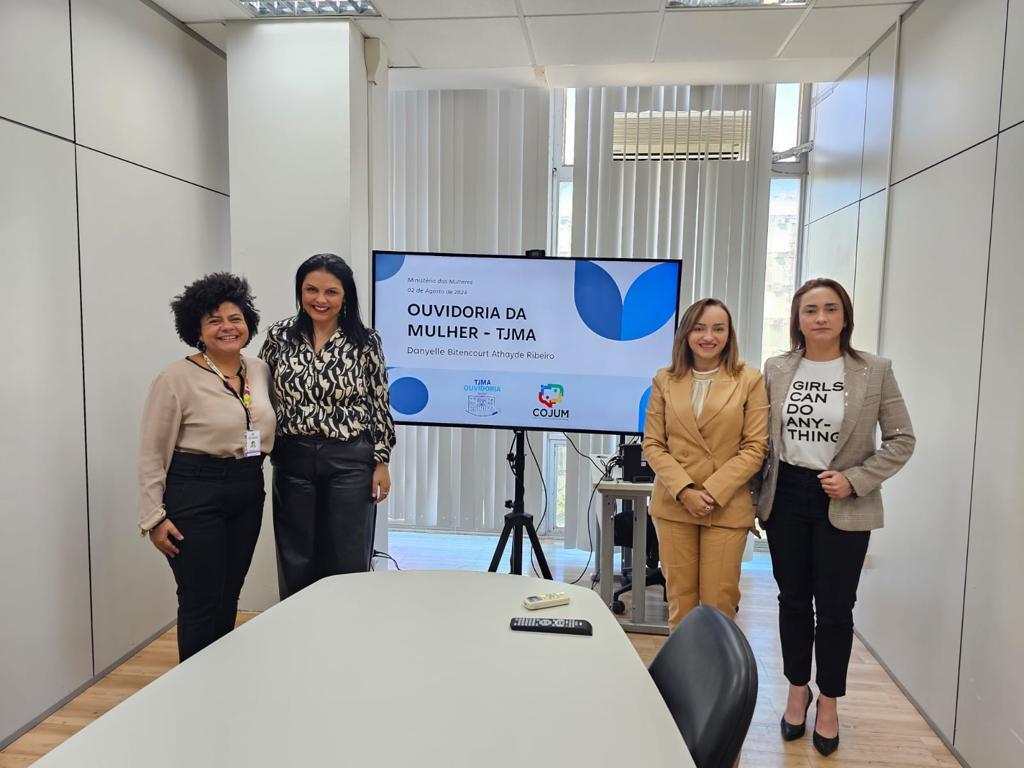 Quatro mulheres em reunião em Brasília. Foto na horizontal, elas estão posicionadas em frente a uma televisão, em uma sala de paredes brandes e teto branco. Na foto: a ouvidora do Ministério das Mulheres, Thaís dos Santos Lima; a desembargadora Tânia Regina Silva Reckziegel; desembargadora eleitoral TRE-CE, Kamille Castro e a Ouvidora da Mulher TJMA, Danyelle Bitencourt