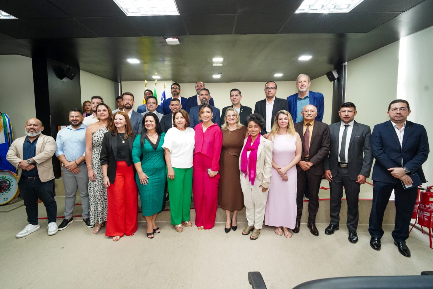 grupo de pessoas vestindo formalmente, lado a lado, em ambiente externo.