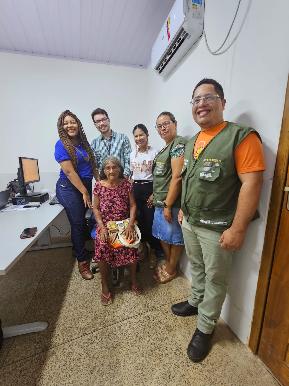 Grupo de cinco pessoas do TJMA e Defensoria em pé, proximo a uma idosa indigena q está sentada