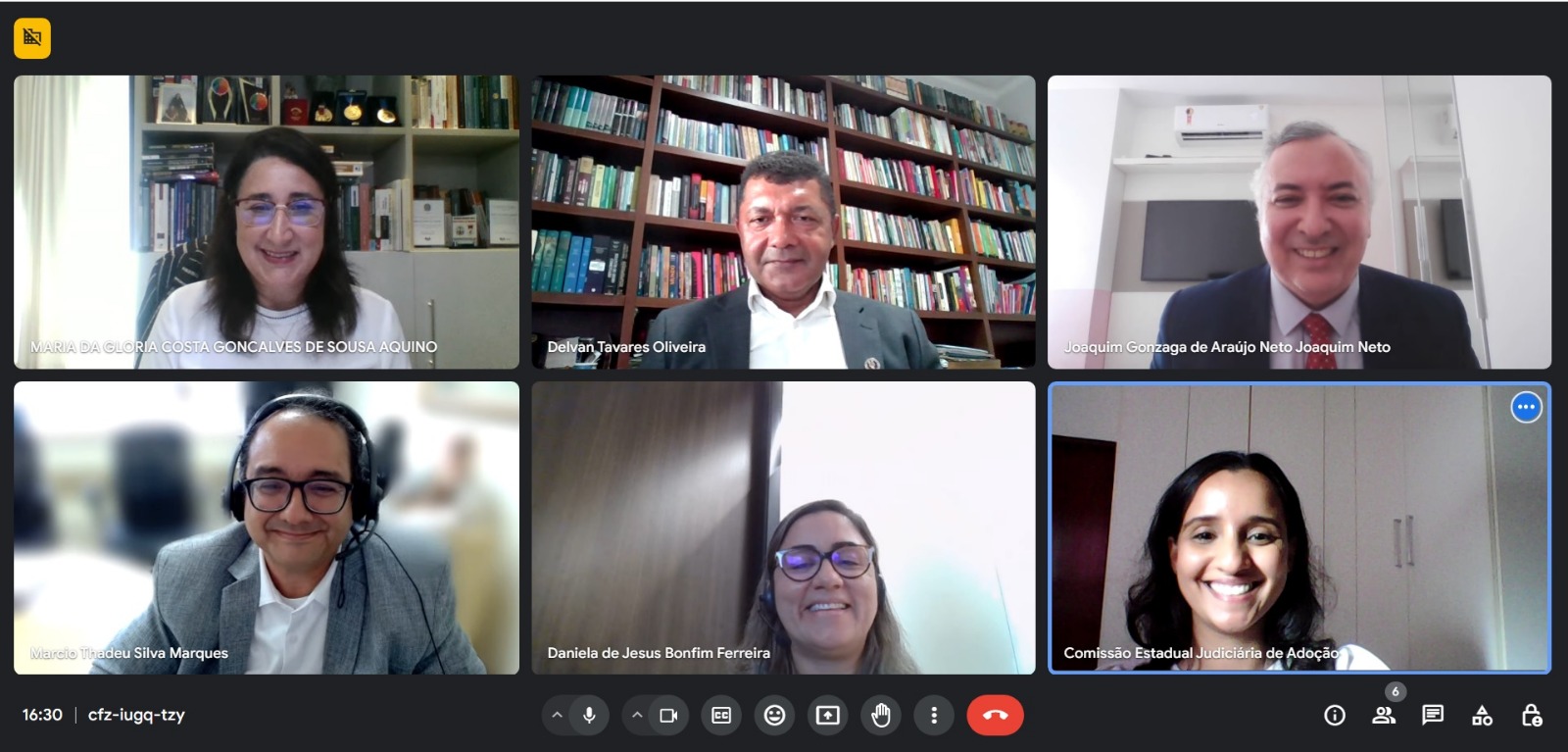 A imagem mostra uma captura de tela de uma reunião virtual com seis participantes. Cada participante é representado por um vídeo separado, organizados em duas fileiras. A fileira superior tem três vídeos e a inferior também tem três. Todos os rostos estão anonimizados com retângulos marrons para proteger a privacidade. O fundo do vídeo do meio na fileira superior mostra uma estante cheia de livros, indicando que pode ser uma sala de escritório ou biblioteca pessoal.
