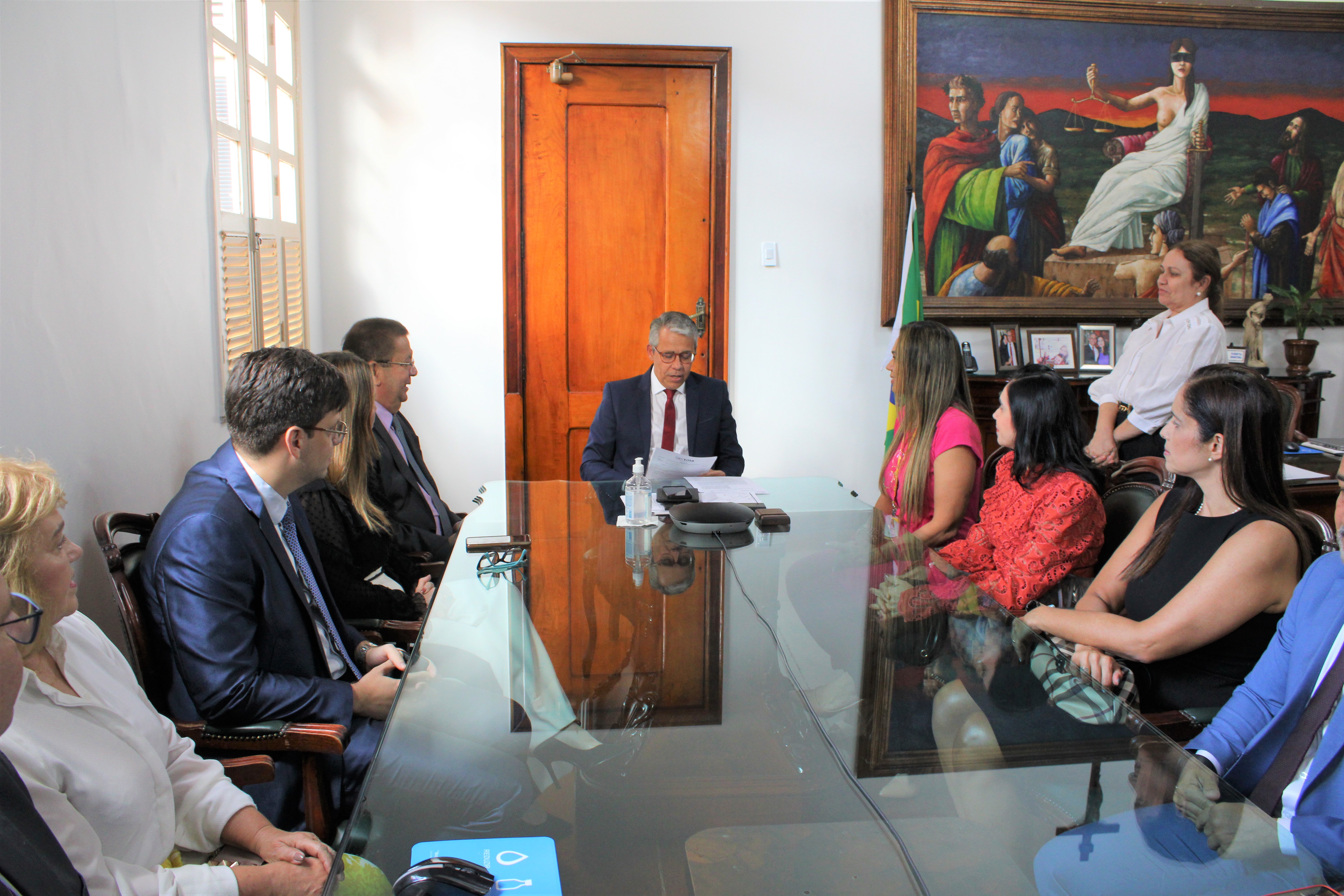 Pessoas sentadas ao redor de mesa, na cabeceira, o presidente do TJMA, desembargador Paulo Velten, acompanhado de integrantes do Comitê de Saúde e do NATJus.