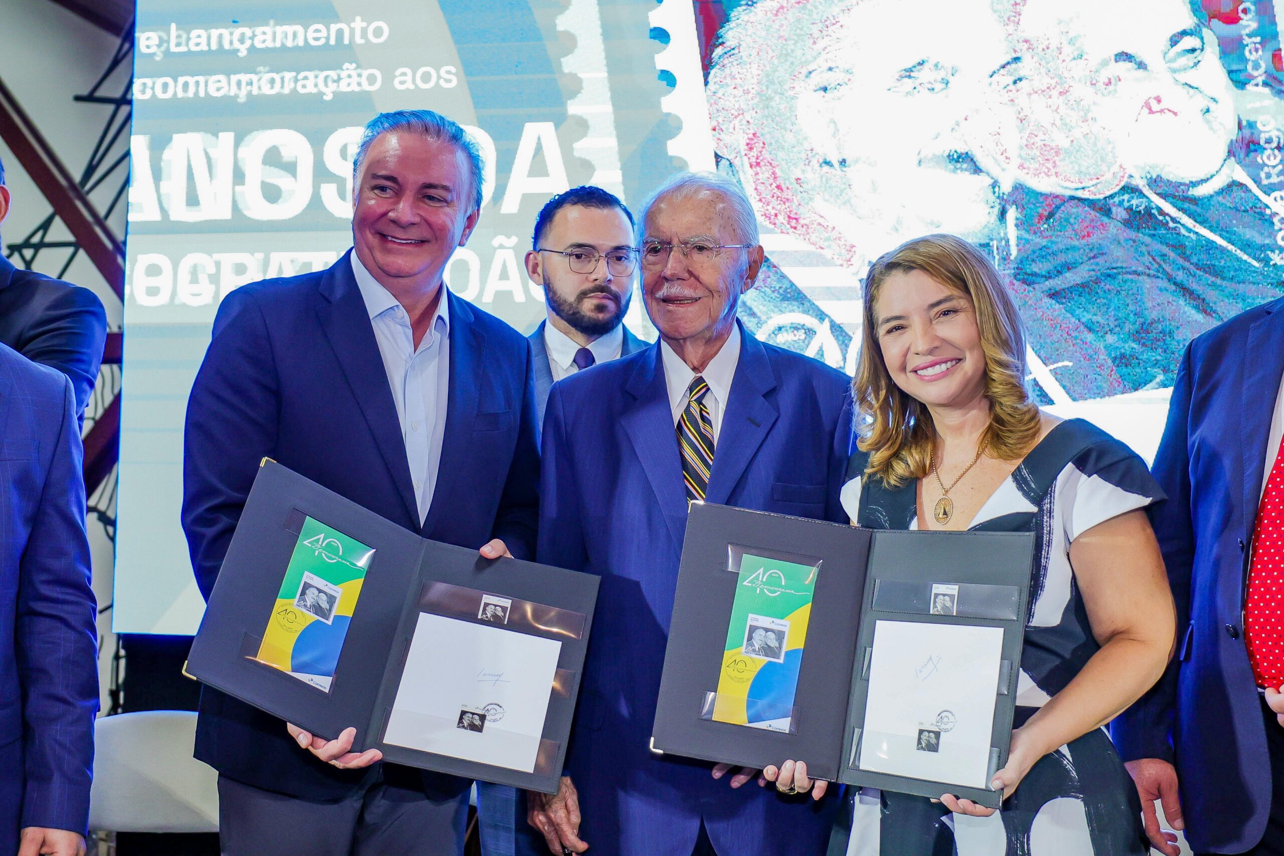 Foto de autoridades com selo do correios lançado, na mão