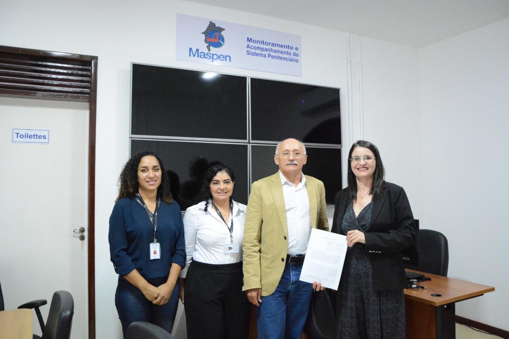 foto colorida. de pé, lado a lado, o juiz José dos Santos Costa, a presidente da FUNAC Sorimar Saboia e duas servidoras, mostrando o termo de cooperação assinado