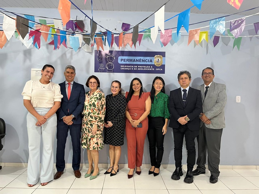 Grupo de pessoas em pé, lado a lado, vestidos formalmente, durante visita institucional às instalações de delegacia da infância e juventude