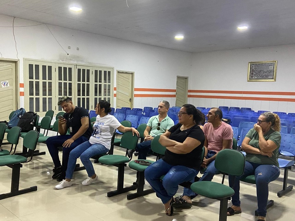 algumas pessoas sentadas em plateia, com cadeiras azuis dispostas em fileiras, aguardando atendimentoi