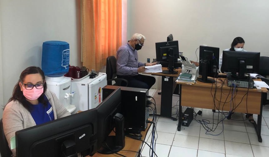 Foto mostra funcionários da Corregedoria trabalhando em mesas diante de computadores