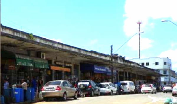 Foto horizontal de fachada do Mercado Central de Sãoo Luís, em perspectiva, com carros parados em frente às lojas.