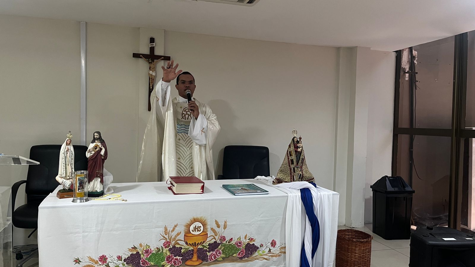 A IMAGEM MOSTRA O PADRE ANDRÉ MARTINS NO ALTAR JUNTAMENTE COM A IMAGEM DA NOSSA SENHORA DE NAZARÉ EM UM ALTAR COM UMA TOALHA BRANCA.