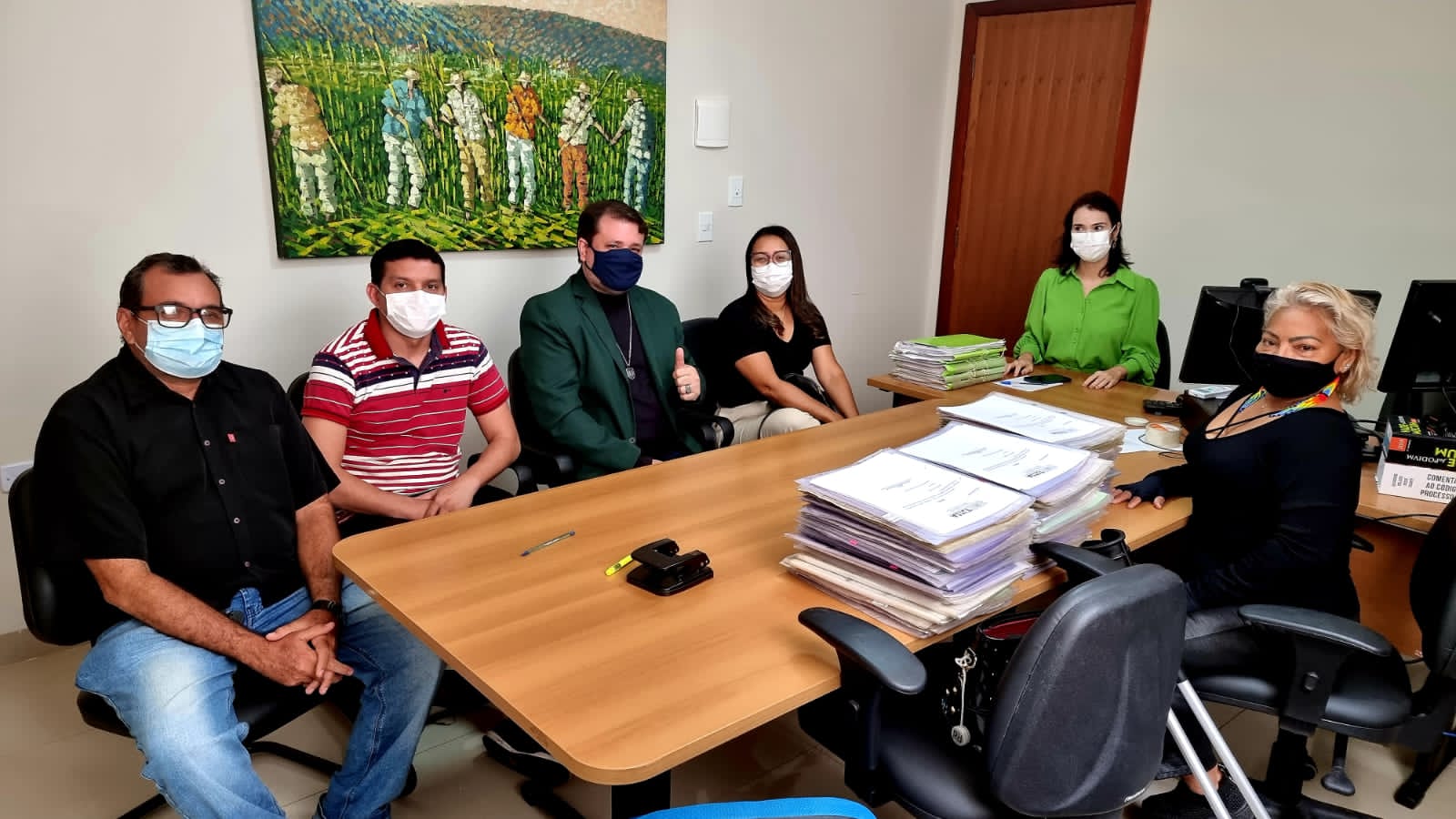 Homens e mulheres sentados à mesa de trabalho, em reunião