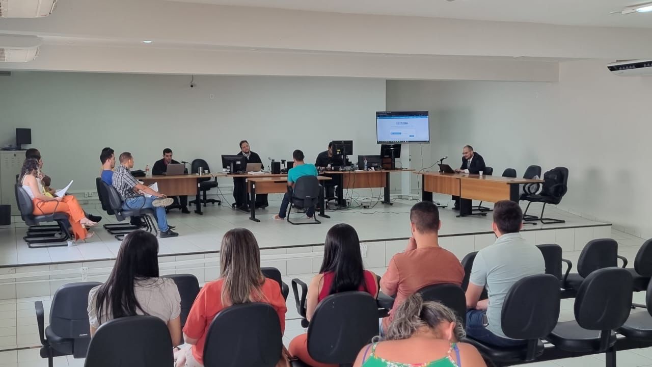 Sessão do Tribunal do Júri, com autoridades judiciárias sentadas em mesa e plateia em auditório