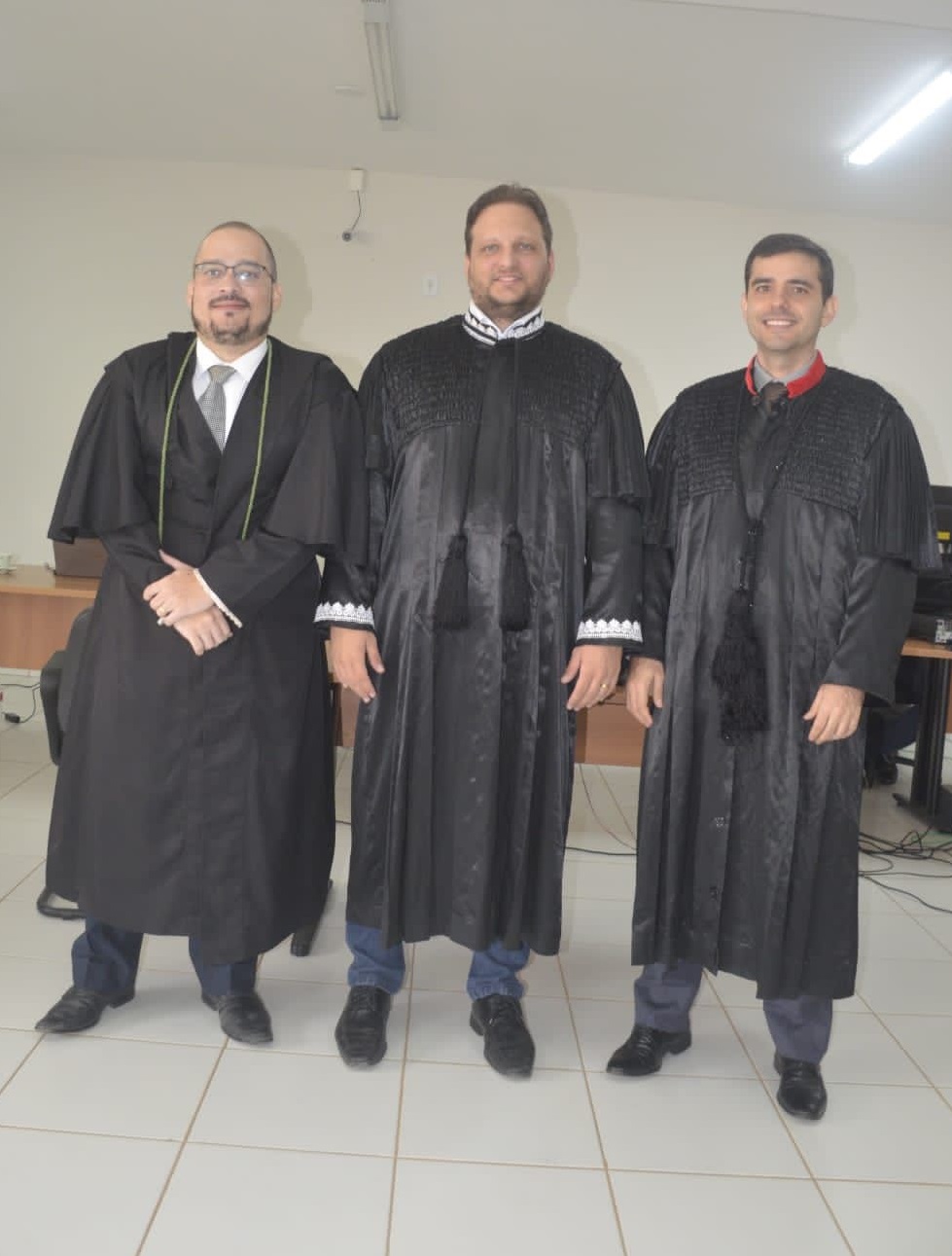 TrÊs homens brancos, de toga preta, de pé, posam pra fto