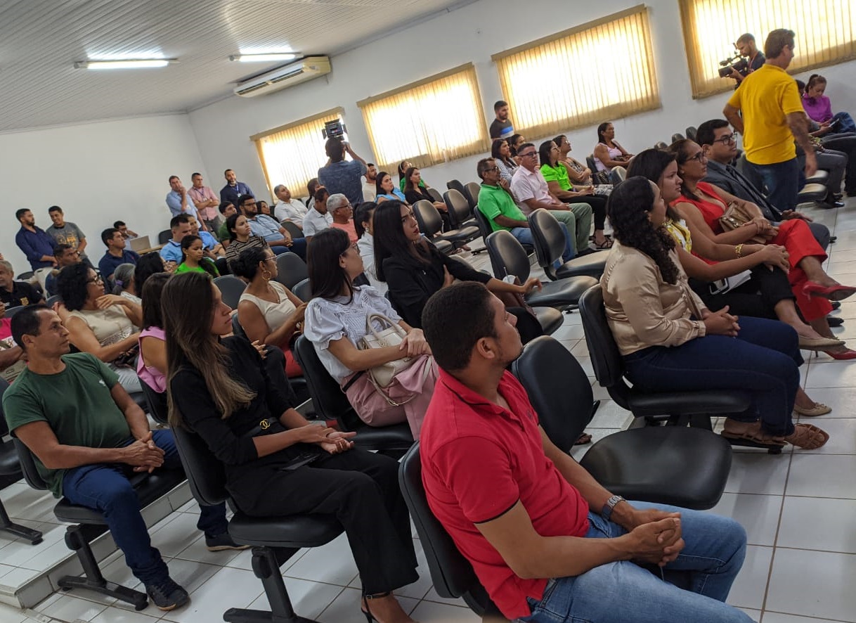 foto horizontal, colorida, de homens e mulheres sentados em cadeiras pretas em salão do júri, de chão e paredes brancas.