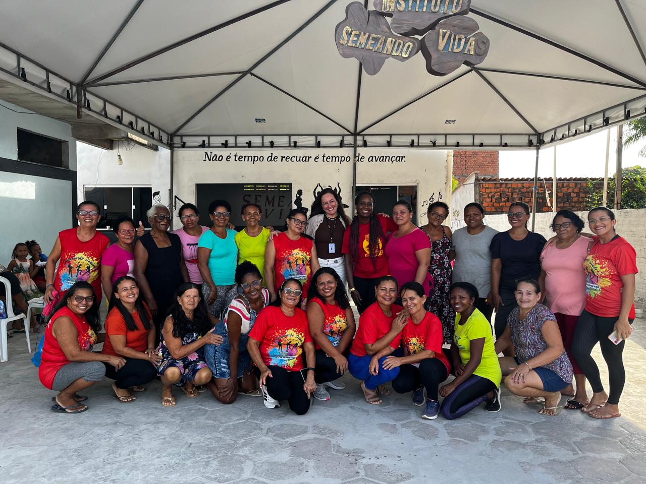 PARTICIPANTES DA PALESTRA ESTÃO SORRINDO NA FOTO. AO FUNDO UMA PLACA DE MADEIRA ESCRITO NOME DA INSTITUIÇÃO "SEMEANDO VIDAS".