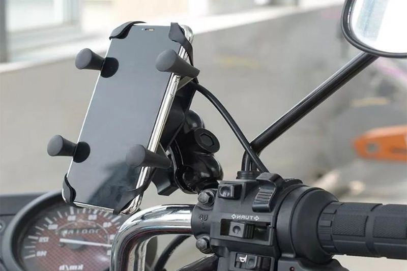 imagem na qual aparece o guidão de uma moto, com um celular no suporte