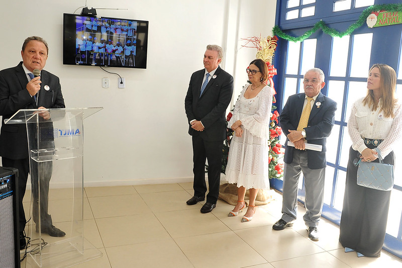 Foto mostra o presidente da Cemulher/TJMA, desembargador Cleones Cunha, falando ao microfone, ao lado de desembargadores e desembargadora.