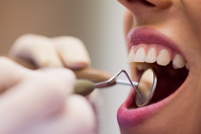 Close em atendimento odontológico. Mulher com boca semiaberta e dentista segurando ferramentas de atendimento odontológico.