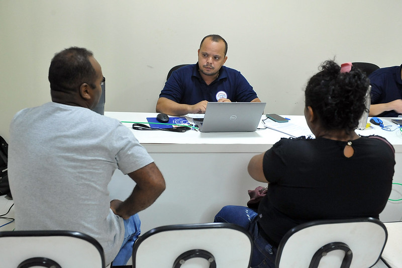 Foto mostra pessoas sentadas sendo atendidas por conciliadores e conciliadoras em uma sala durante o projeto Conciliação Itinerante em Itapecuru.