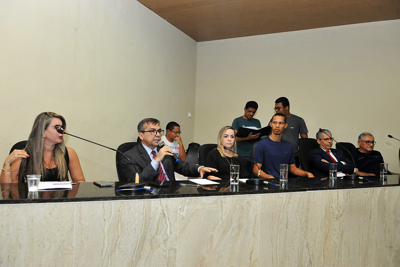 Foto mostra o presidente do Nupemec/TJMA, desembargador José Gonçalo Filho, sentado falando ao microfone para o público. Ao lado dele estão a juíza Mirella Freitas, o presidente do TJMA, desembargador Paulo Velten, e autoridades.