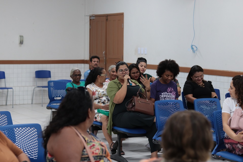 Mulheres sentadas em cadeiras pretas no auditório assistindo a palestra da Cemulher.