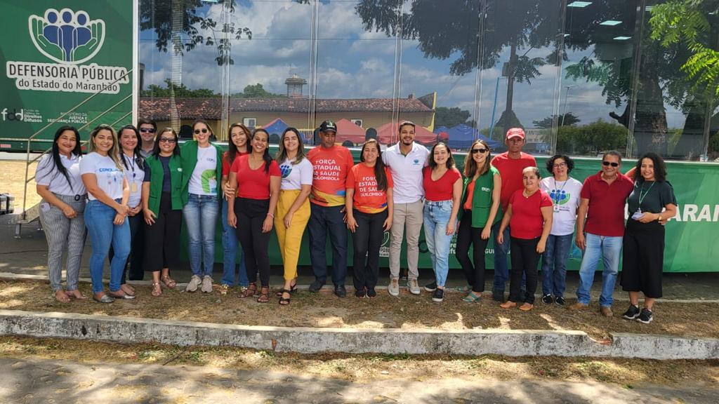 Equipe de conciliadores e conciliadoras do TJMA em pé ao lado de servidores e servidoras da Defensoria, durante evento em Paulino Neves e Belágua